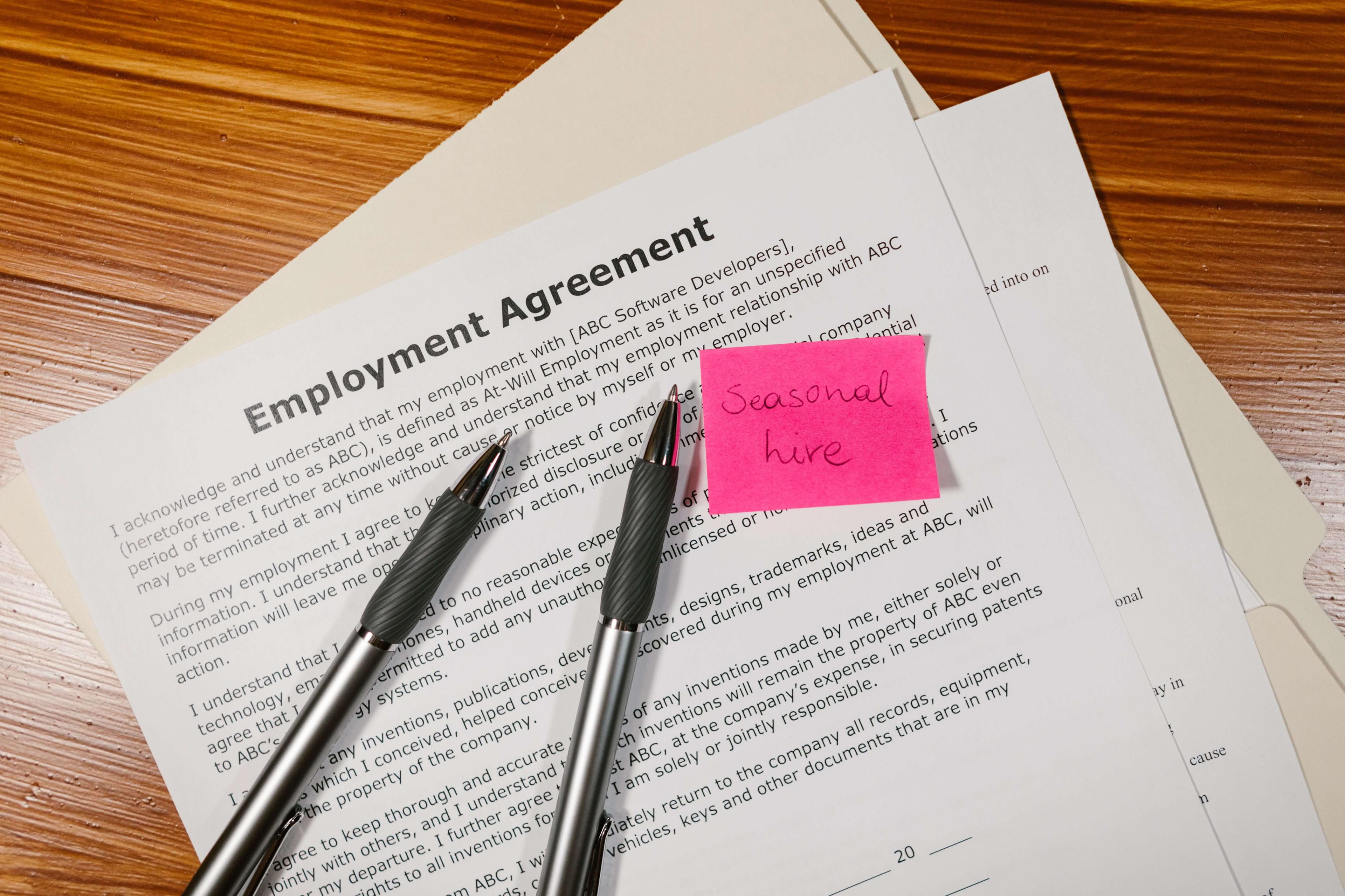 An employment agreement on a desk, with two pens and a file folder